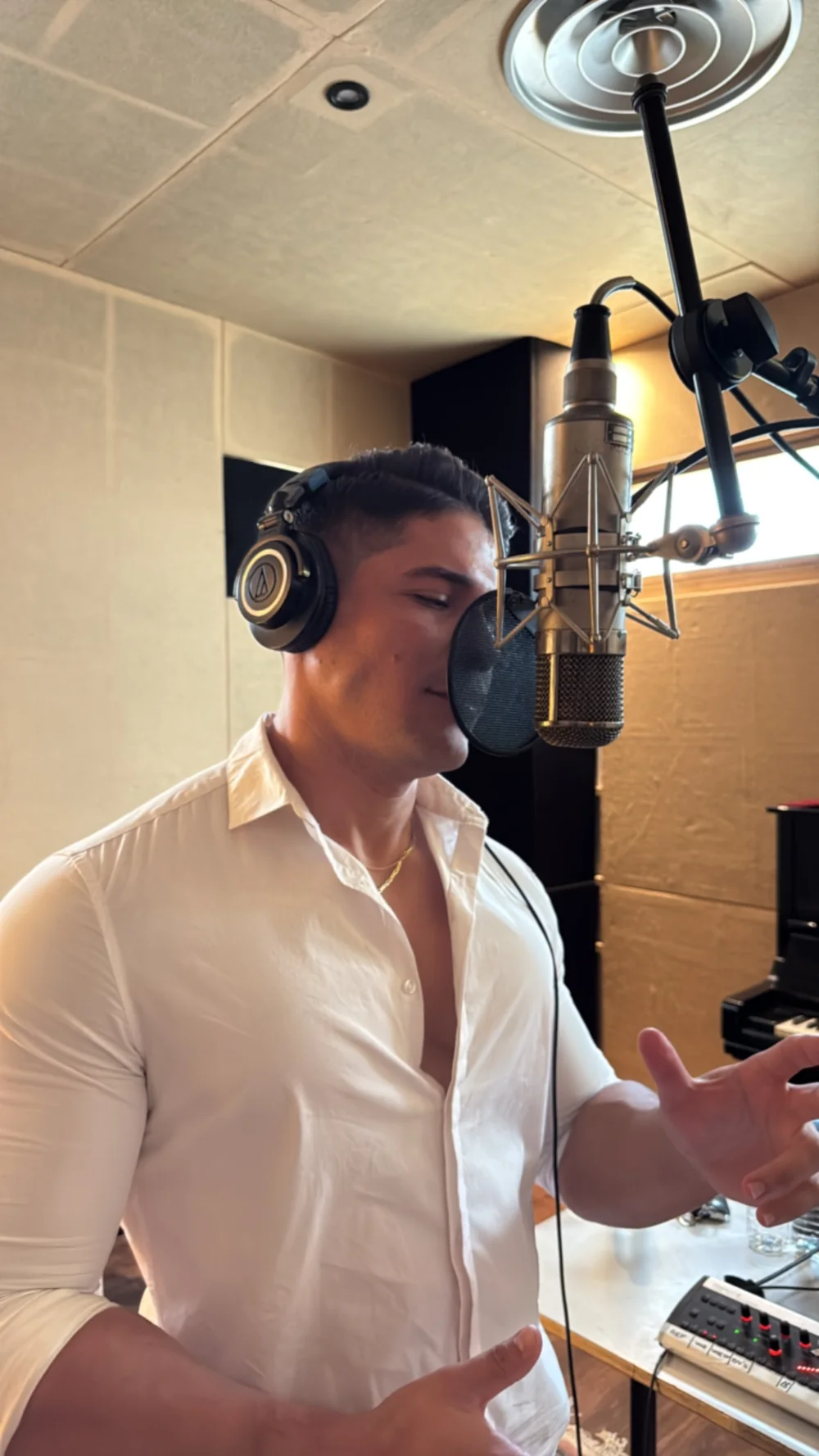Primer plano de GIAN interpretando una canción ante el micrófono del estudio