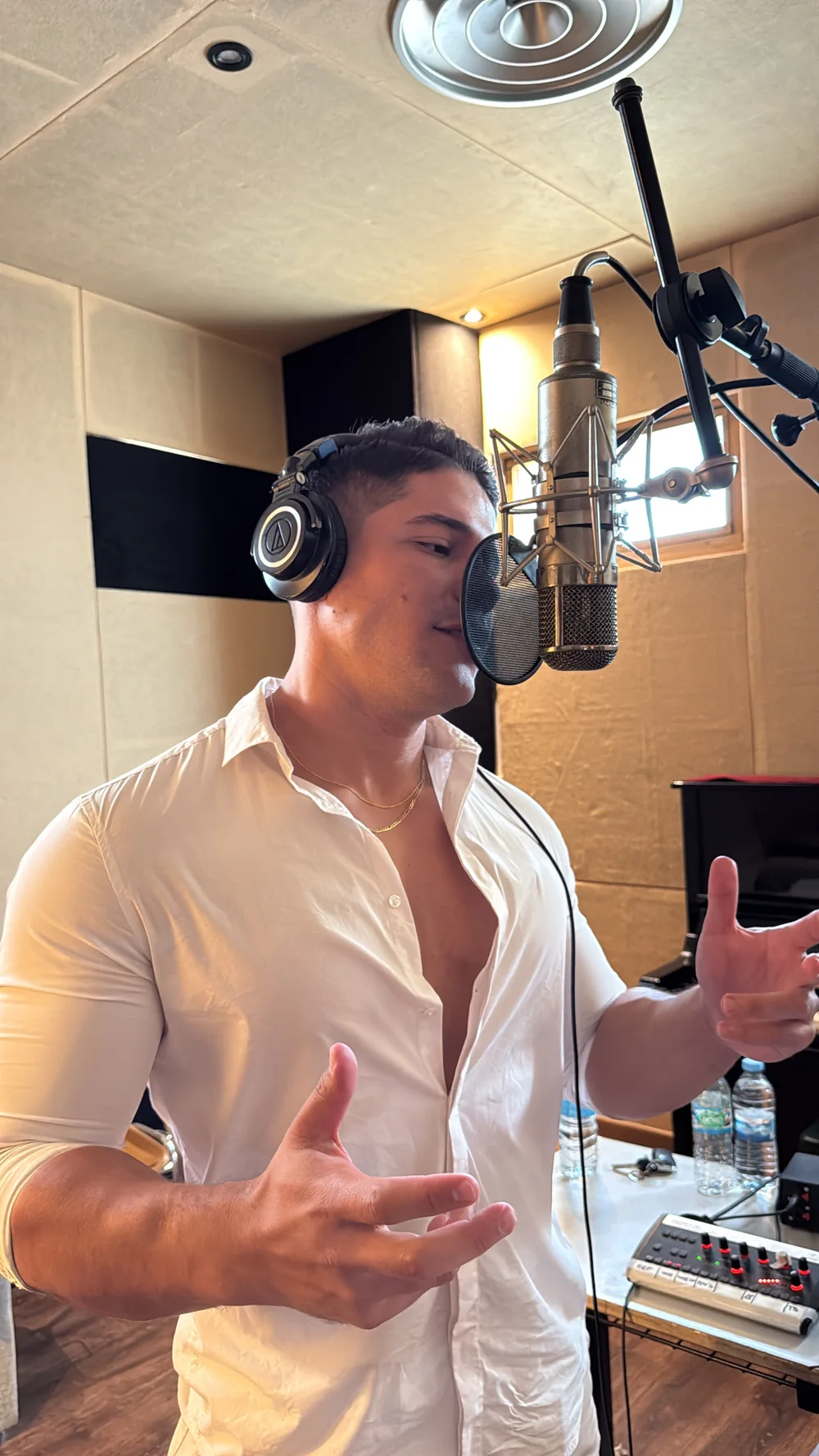 GIAN interpretando una canción en el estudio con camisa blanca