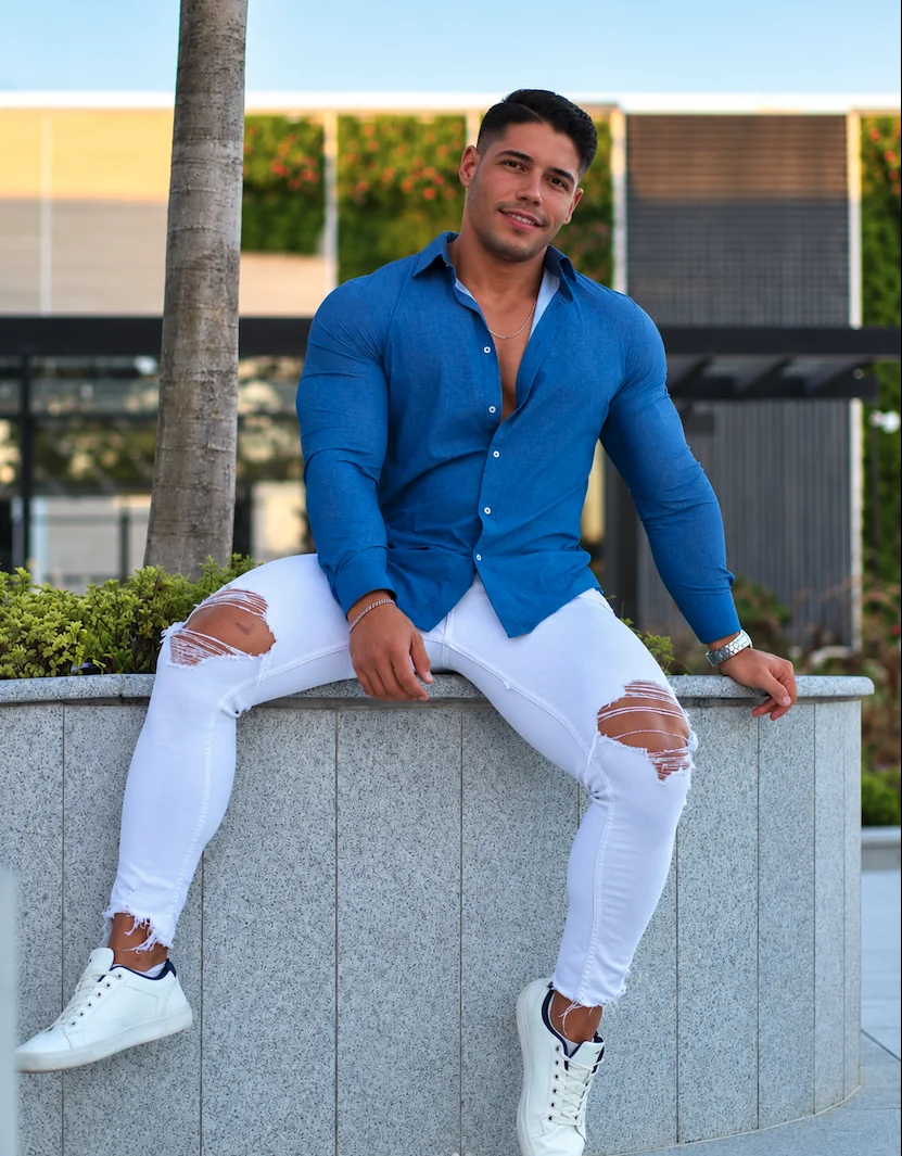 GIAN con camisa azul y pantalón blanco en una terraza